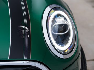 Een close-up van de koplampen van een groene MINI Cooper S.