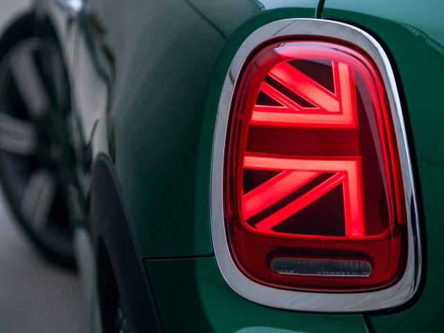 Het achterlicht van een groene MINI Cooper S met een Britse vlag erop.