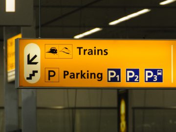 Een geel en zwart bord "Auto parkeren vliegveld" op een luchthaven.