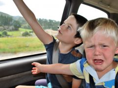 Twee kinderen zitten op de achterbank van een auto.