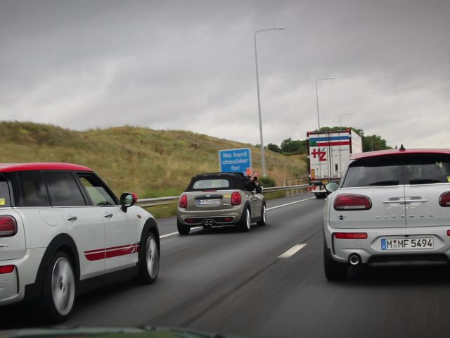 Een groep MINI Cooper S-auto's rijdt over een snelweg.