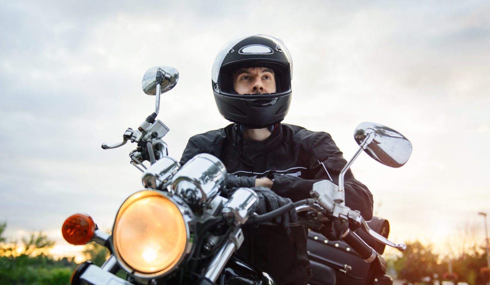 Een man met een motorhelm op een motorfiets.
