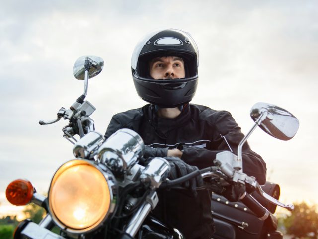 Een man met een motorhelm op een motorfiets.