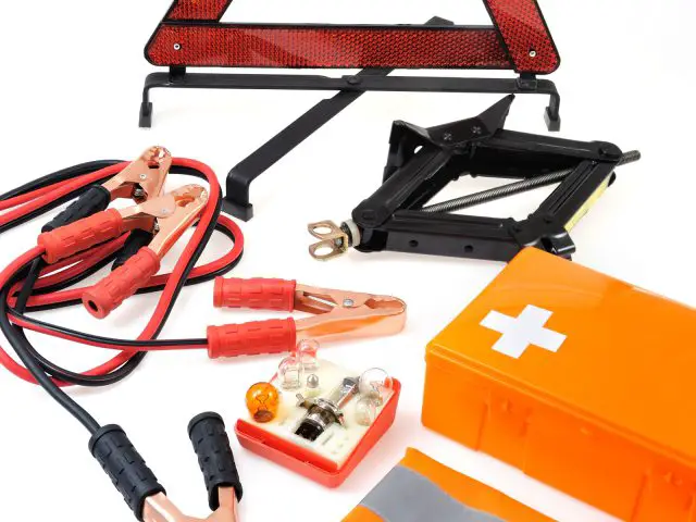 Een set auto-accessoires voor noodgevallen, waaronder een driehoek, een zaklamp en een set startkabels.