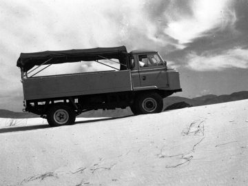 Een oude zwart-witfoto van een Defender-truck in de woestijn.
