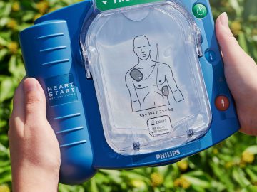 Een persoon die een AED-apparaat in zijn handen houdt.
