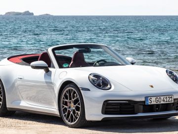 De witte Porsche 911 cabrio, tentoongesteld op de IAA, geparkeerd op het strand.