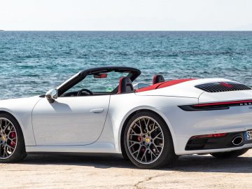 De witte Porsche 911 Targa, tentoongesteld op de IAA, geparkeerd op het strand.