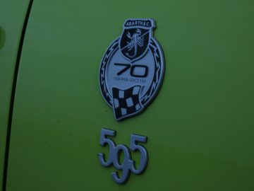 Een groene auto met een Abarth-badge op de motorkap.