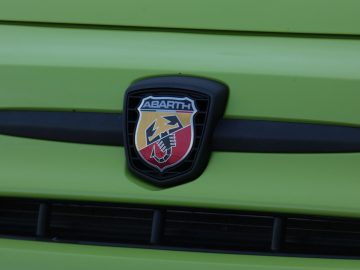 Een groene auto met een Abarth-embleem op de grille.