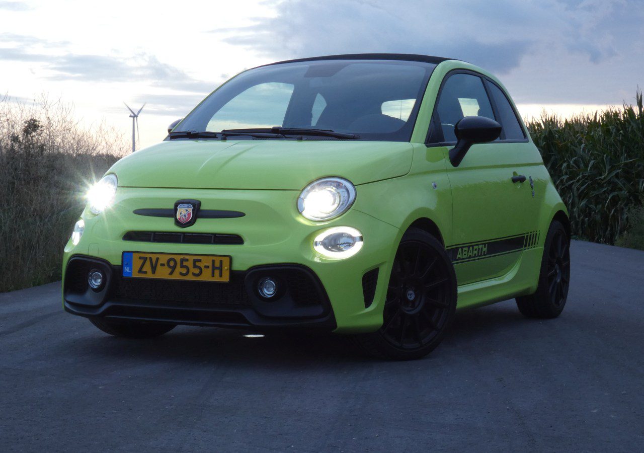Een groene Fiat 500 Abarth rijdt over een landweg.