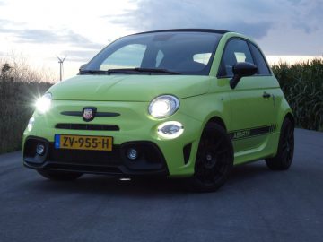 Een groene Fiat 500 Abarth rijdt over een landweg.