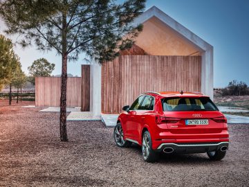 Een rode Audi RS Q3 geparkeerd voor een houten huis.