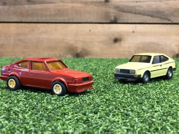 Twee Skoda Rapid Coupé-speelgoedauto's op een grasveld.
