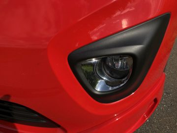 Een close-up van de koplampen van een rode Opel Vivaro.