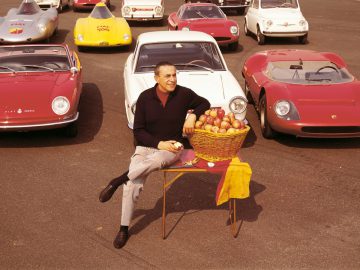 Een man zit op een tafel met een mandje met Abarth-appels.