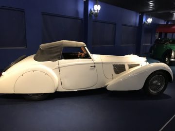 In het museum Cité de l'Automobile staat een witte vintage auto tentoongesteld.