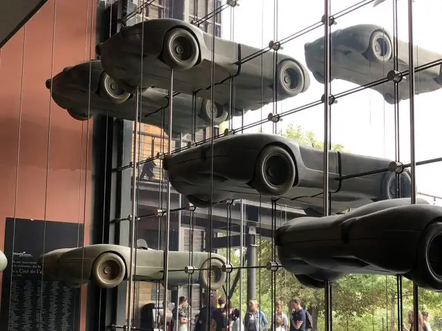 Een groep auto's die aan een glazen wand hangen in het Cité de l'Automobile museum.