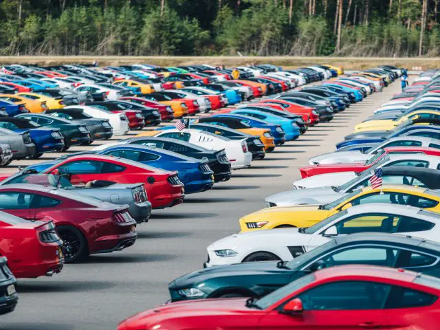 Veel auto's, waaronder een Ford Mustang, geparkeerd op een parkeerplaats.