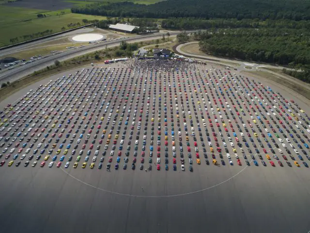 Een luchtfoto van een grote parkeerplaats vol auto's, waaronder een Ford Mustang.