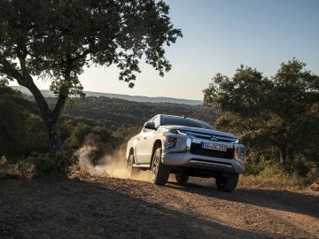 De Mitsubishi L200 rijdt over een onverharde weg.