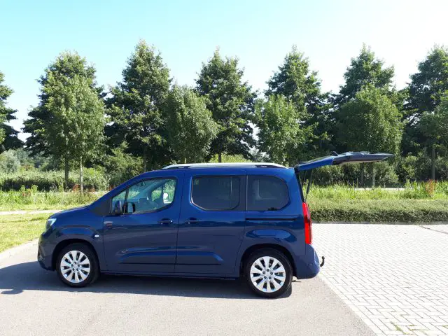 Een kleine blauwe Opel Combo Tour geparkeerd op een parkeerplaats.