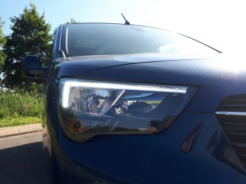 Een close-up van de koplampen van een blauwe Opel Combo Tour.