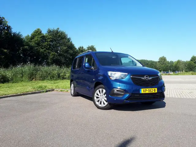 Een blauw Opel Combo Tour-busje geparkeerd op een parkeerplaats.