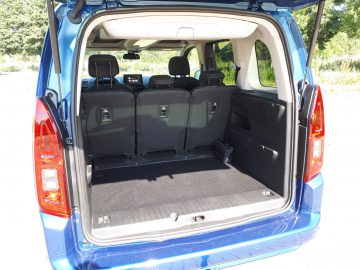 De achterkant van een blauwe Opel Combo Tour met de stoelen open.