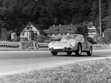 Een vintage foto van een Porsche-raceauto die over een weg rijdt.