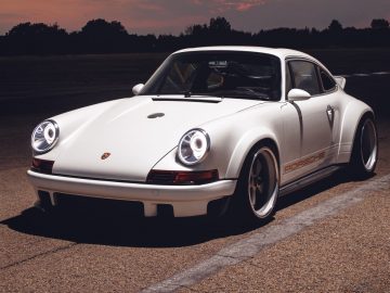 Een Porsche geparkeerd op een circuit bij zonsondergang.
