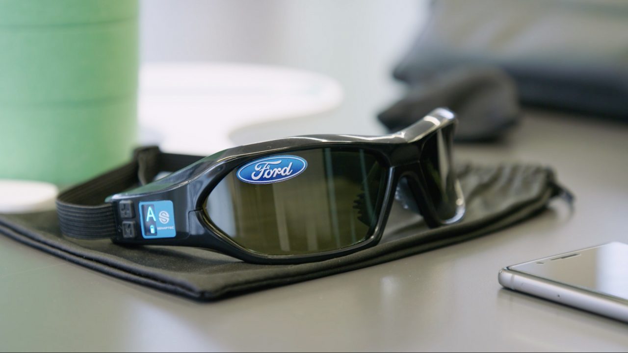 Een Ford-slaappak-bril op een bureau naast een mobiele telefoon.