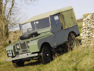 Een groene Land Rover Defender geparkeerd in een veld.