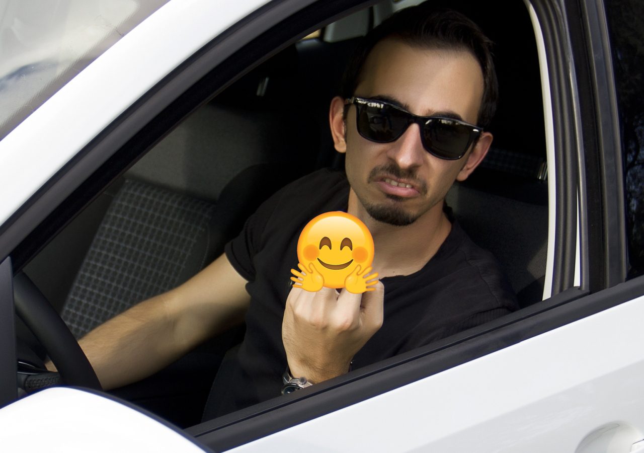 Een automobilist zit in een auto met een smiley op zijn gezicht.