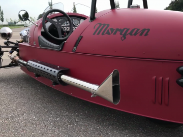 Een rode Morgan 3 Wheeler met het woord Morgan erop.