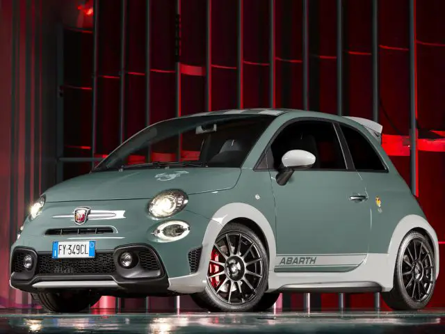 Een groene Abarth 695 70° Anniversario staat geparkeerd voor een rood licht.