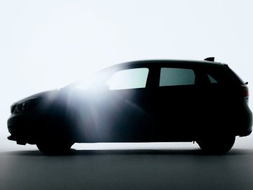 Een silhouet van een kleine Honda Jazz voor een fel licht.