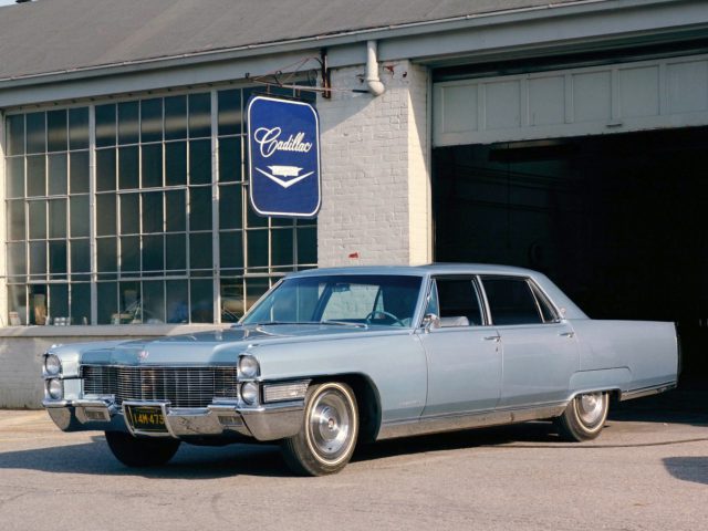 Een blauwe Cadillac met stoelverwarming geparkeerd voor een garage.