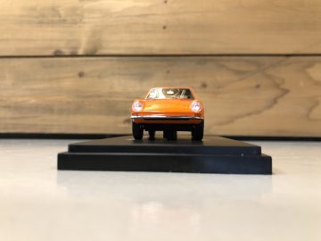 Een kleine oranje DAF 40 GT modelauto op houten onderstel.