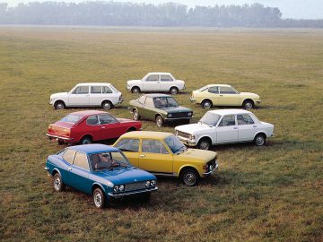 Een groep Fiat 128-auto's geparkeerd in een veld.