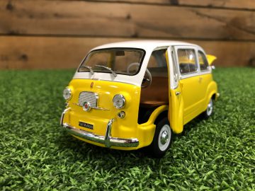 Een geel-witte Fiat 600 Multipla speelgoedauto zittend op gras.