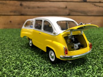 Een gele Fiat 600 Multipla speelgoedauto met zijn kofferbak open op gras.