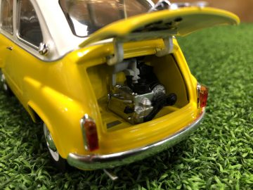 Een gele Fiat 600 Multipla speelgoedauto met zijn kofferbak open op gras.