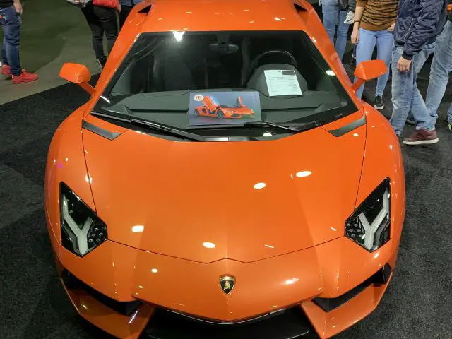Een 100% Auto Live 2019 oranje Lamborghini is te zien op een autoshow.
