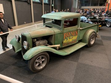 Een oude groene vrachtwagen staat tentoongesteld in een automuseum.