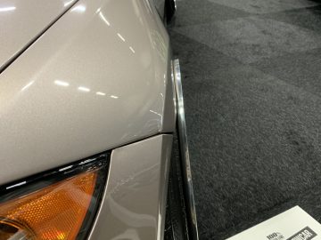 Op de beursvloer van 100% Auto Live 2019 staat een auto geparkeerd met een bord erop.