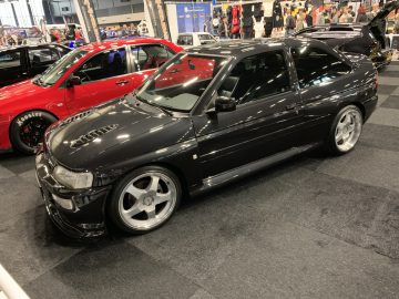 Een zwarte auto staat geparkeerd in een showroom op de 100% Auto Live 2019.