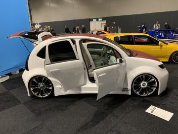 Een witte auto met open deuren op de 100% Auto Live 2019-show.