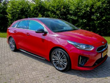 Een rode Kia Proceed geparkeerd op een stenen oprit.
