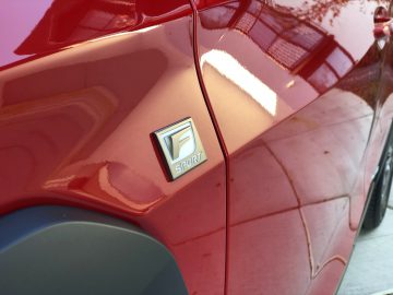 Een close-up van het embleem op een rode Lexus UX-auto.